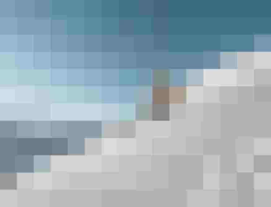 Skifahrerin auf frisch präparierter Piste vor verschneiten Bergen